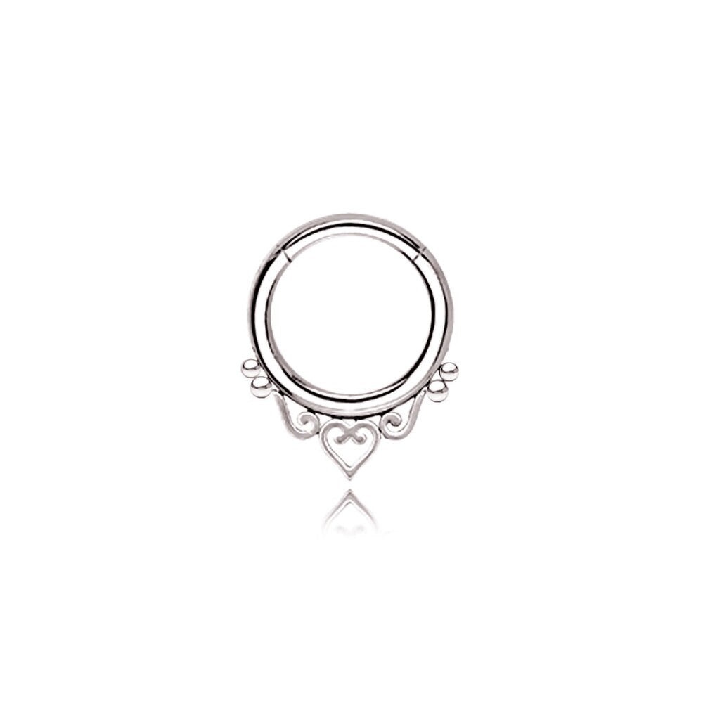 A minimalist septum ring from Kaya Movement, inspired by mandala designs and crafted from high-quality 316L steel, features a silver look under the name "Zura." The design showcases delicate heart detailing at the bottom and includes two small loops flanking the central heart, adding ornamental elegance to the piece. Available in 1.2mm gauge with diameters of 6mm, 8mm, or 10mm, this septum ring stands out against a white background for an eye-catching focal point.